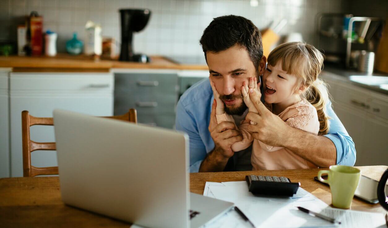 father working on his small business while spending time with his daughter