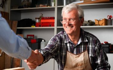Senior small business owner shaking hands with customer