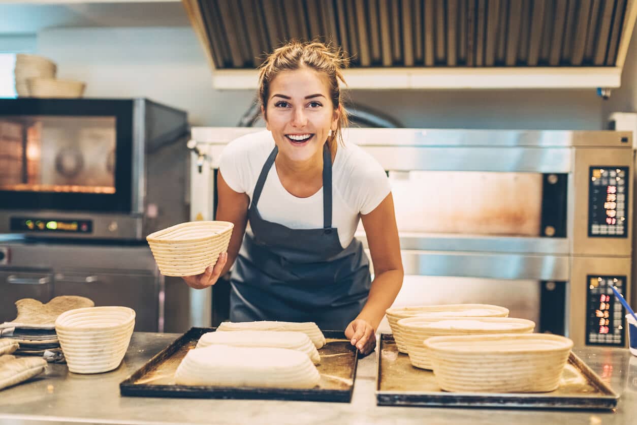 Young woman working in a bakery preparing the bread for baking.