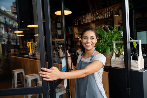 Happy business owner opening the door to her cafe