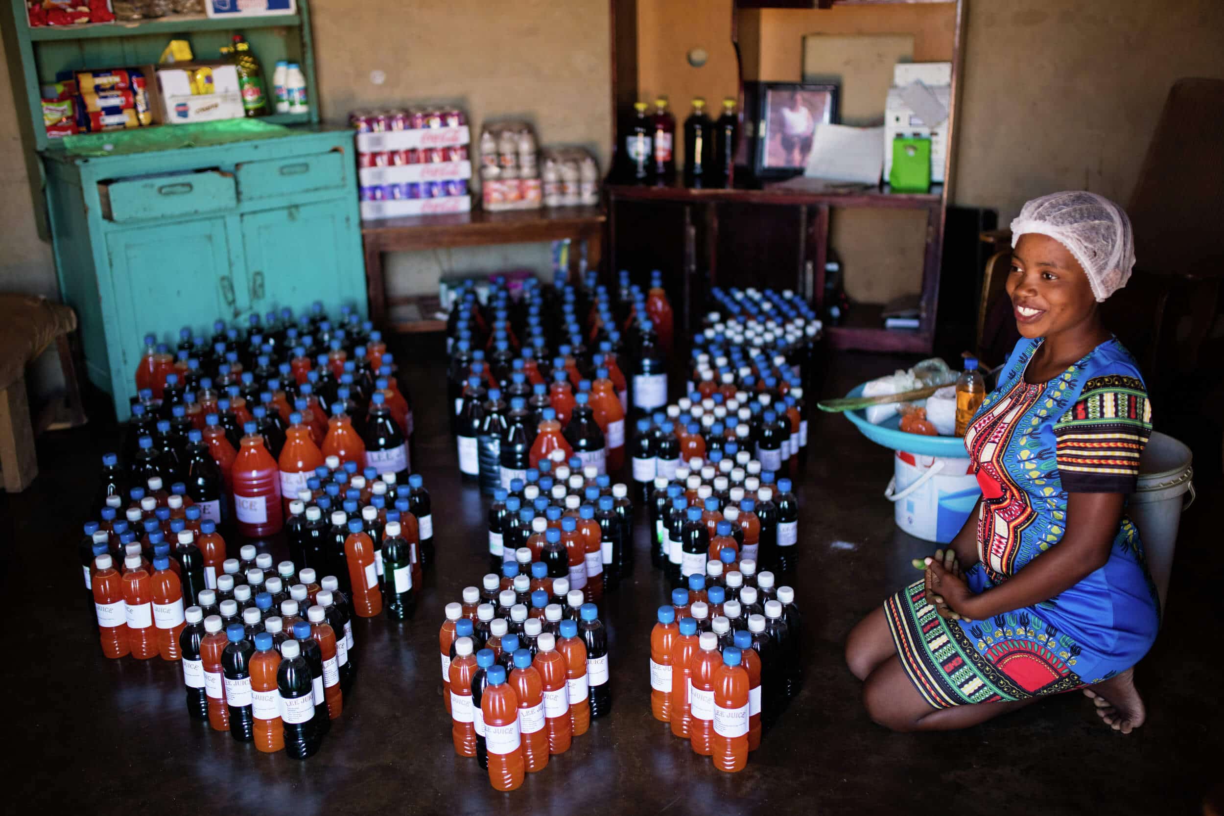 Woman business owner kneeling on floor with bottled sodas