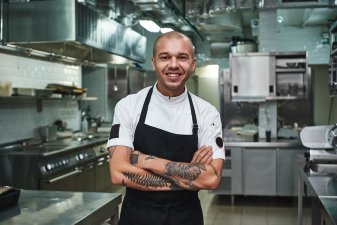 Happy restaurant business owner standing in kitchen