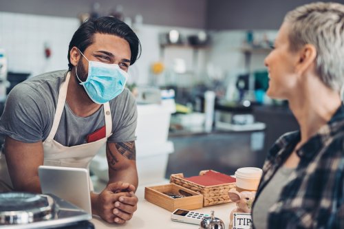 Small business owner wearing a mask and speaking with a customer