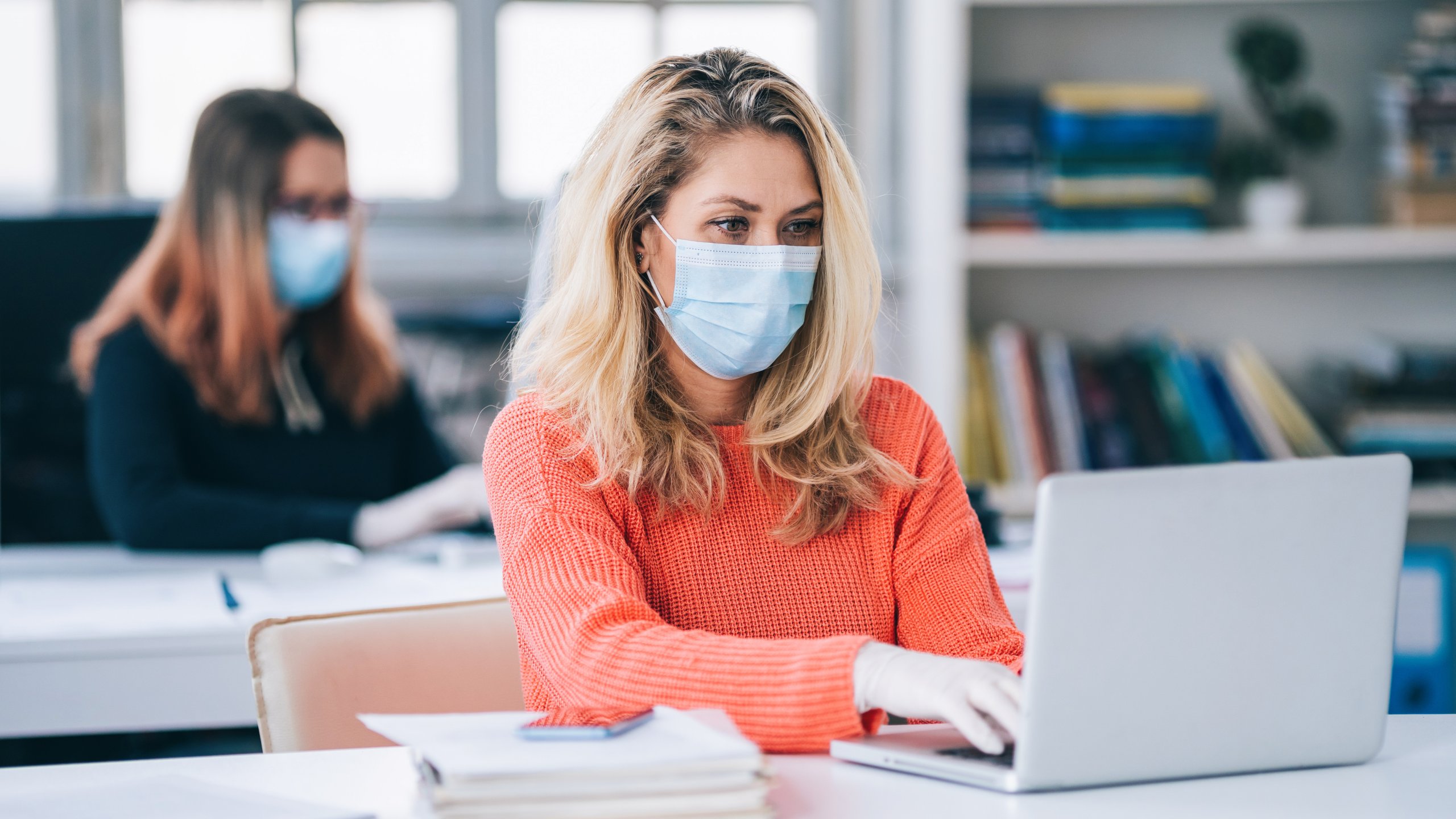 Colleagues in the office working while wearing medical face mask during COVID-19