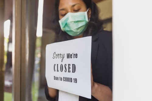 Small business owner putting a closing down poster into a window during Covid 19 outbreak