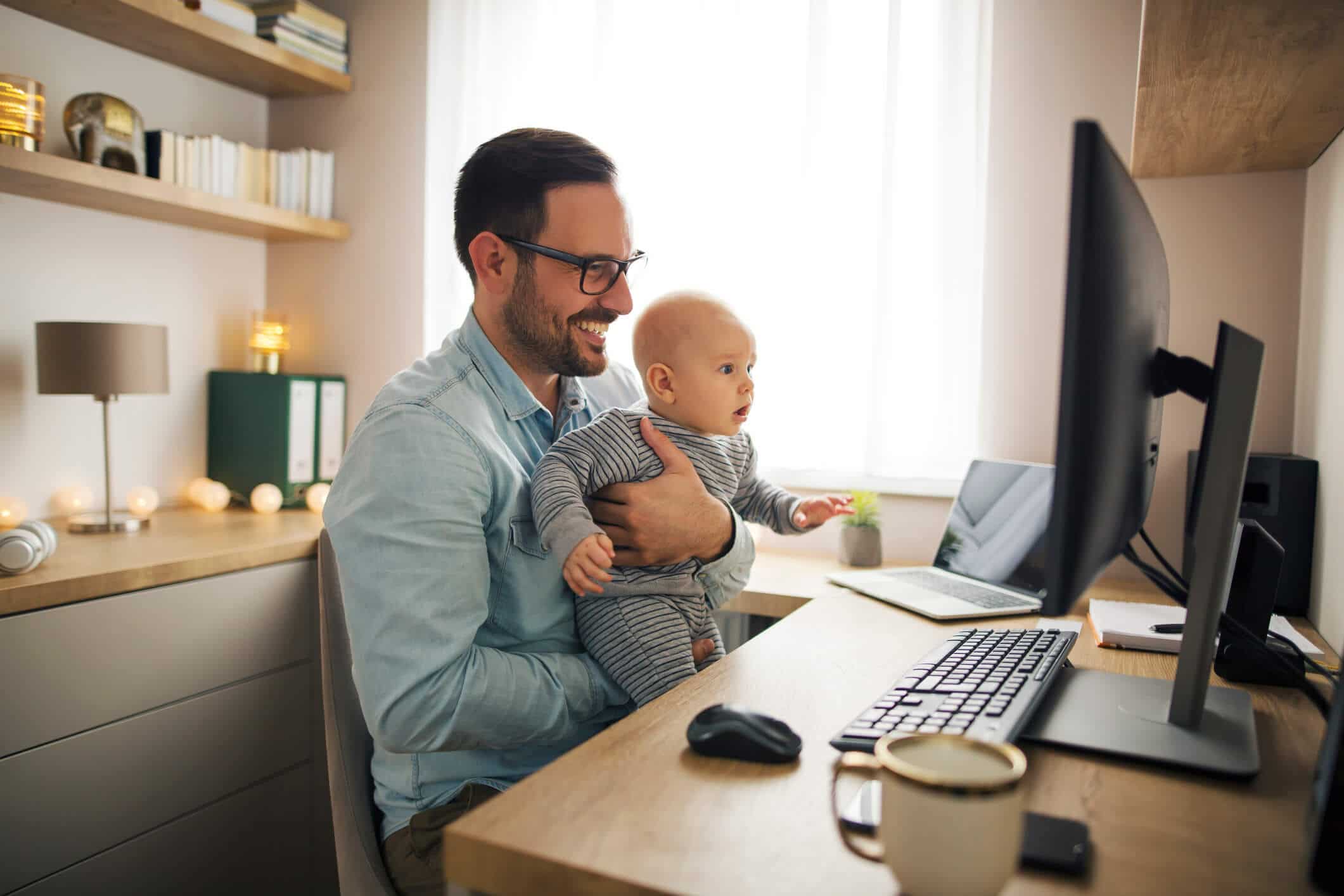 Man holding his child while working from home