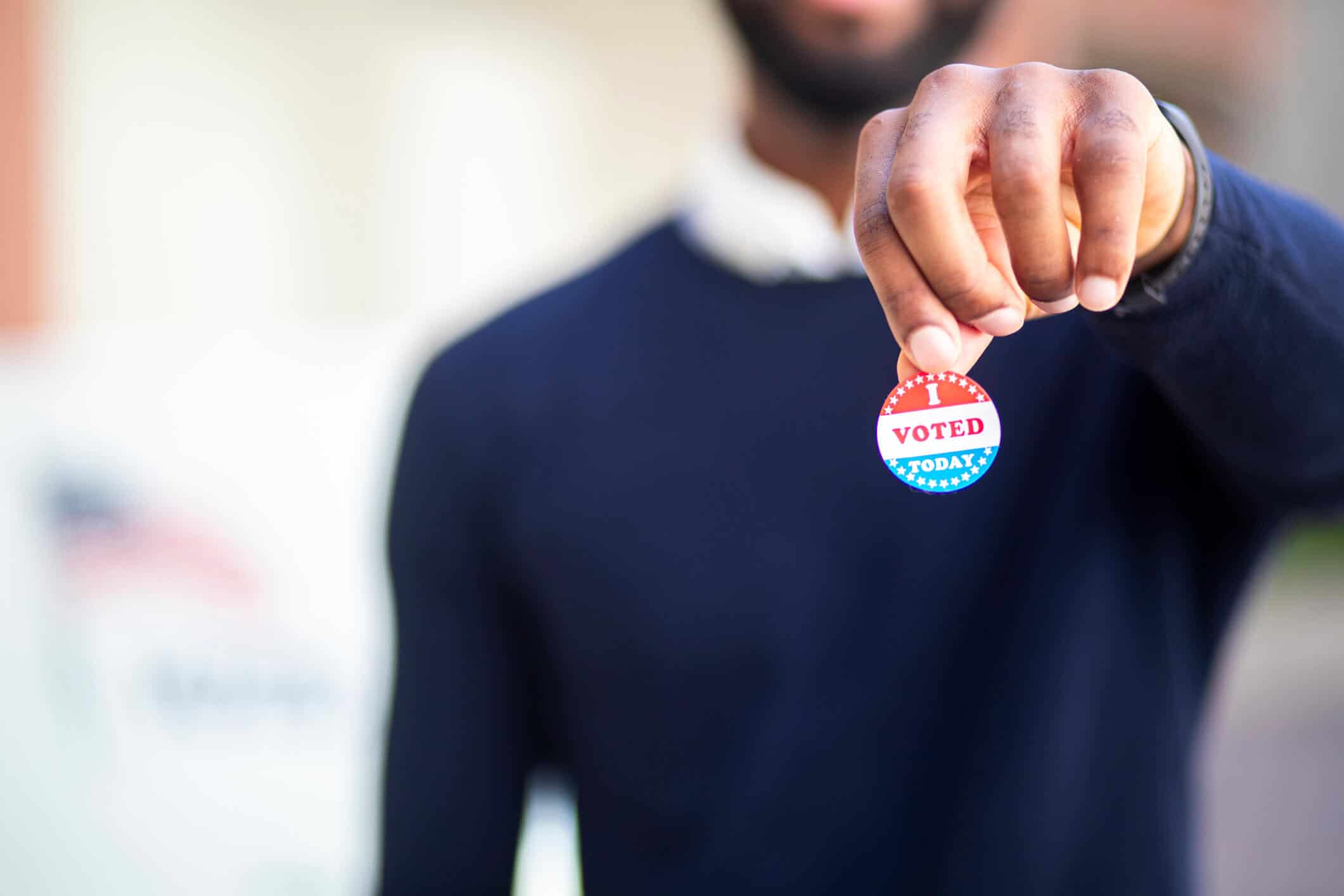 Young black business owner holding an "I Voted" sticker