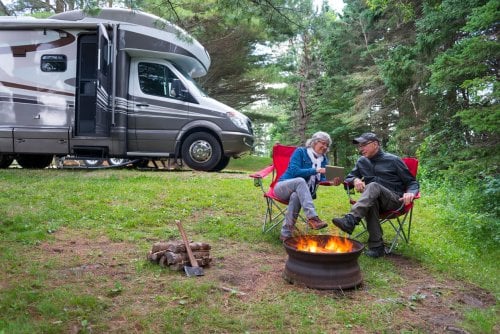Couple sitting outside RV by the fire