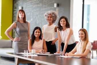 Five female business leaders smiling at a meeting