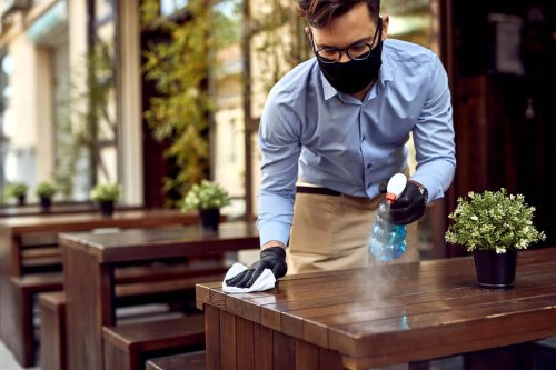 Waiter wearing mask sprays restaurant