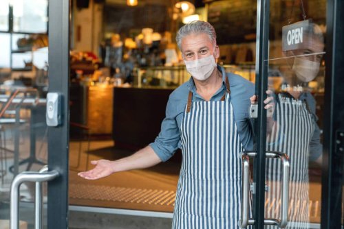 Small Business Owner wearing a mask at the door