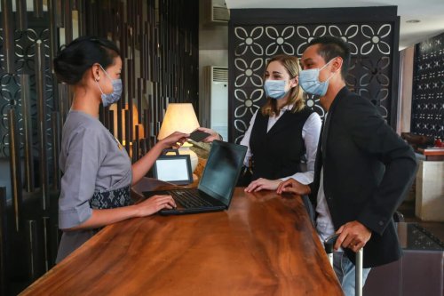 Couple and receptionist wearing masks at a hotel
