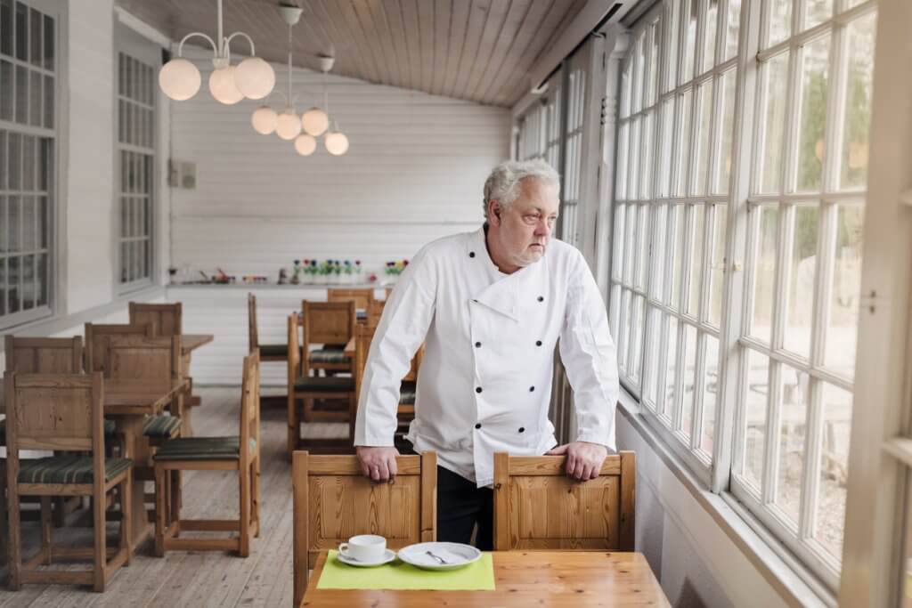 Restaurant owner in his empty restaurant looking out the window.