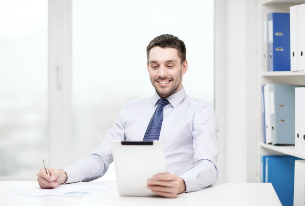 Smiling businessman using a tablet at his desk