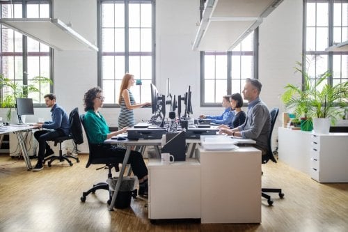 Business people at their desks in a busy, open plan office