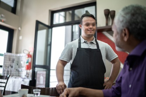 Special needs waiter serving coffee to customer in a coffee shop