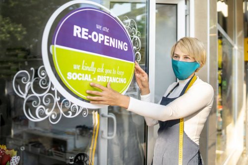 Business owner hanging and open sign on her shop after Coronavirus pandemic