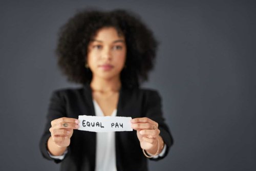 Business Woman holding a piece of paper with Equal Pay written on it