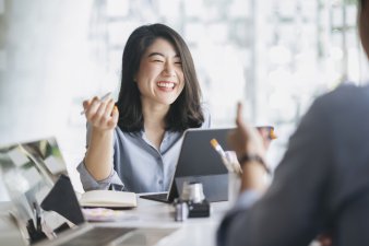Young Asian businesswoman smiles at desk