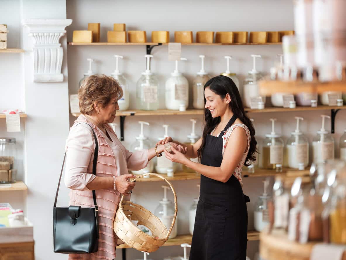 Employee helps senior woman inside food retail store
