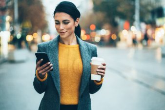 Professional woman holding phone and cup of coffee
