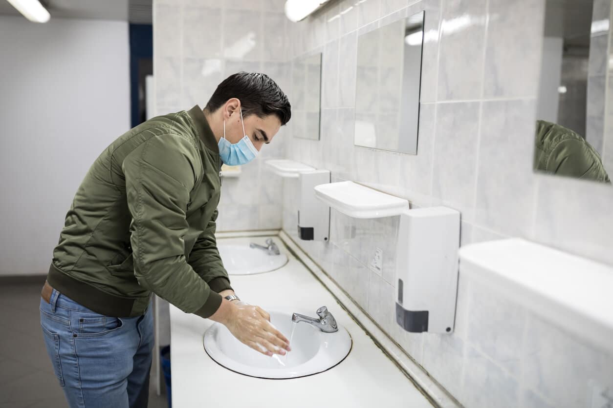 Man wearing a face mask washes his hands