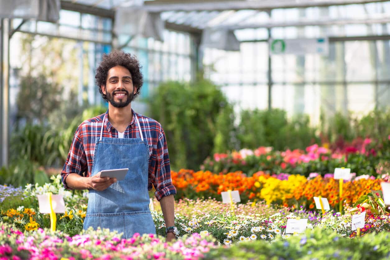 Happy hispanic man working in plant store