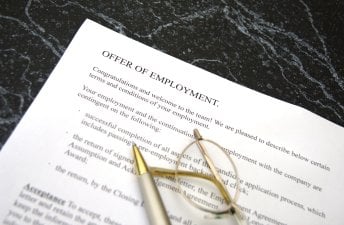 Offer of employment letter with glasses and pen on top of it.