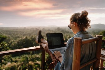 Woman works on laptop in a tropical area at sunset