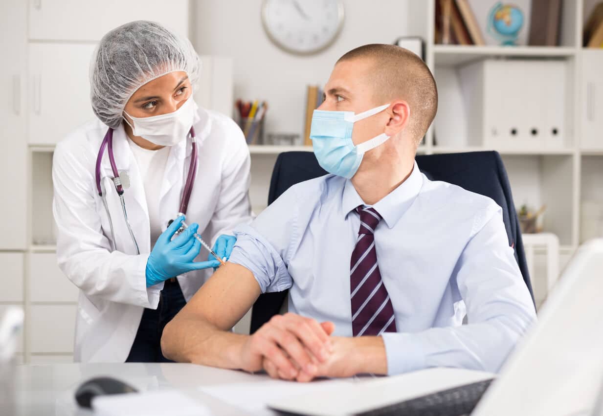 Doctor giving employee a COVID-19 vaccine shot
