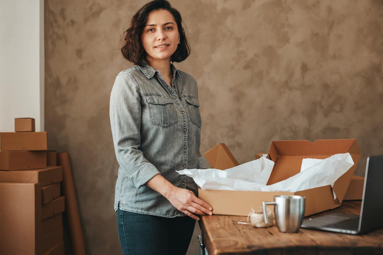 Female business owner putting a shirt in a box to ship