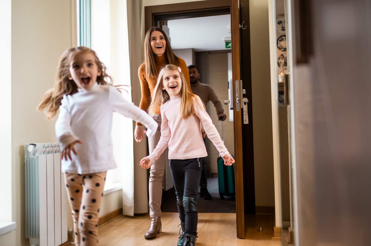 Mother and two daughters look excited as they enter their hotel room