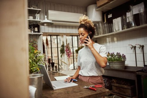 Woman business owner talking on the phone while working on laptop