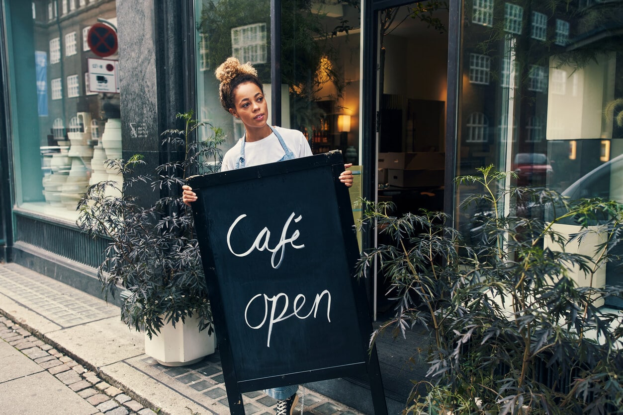 Woman placing an open sign outside of a cafe
