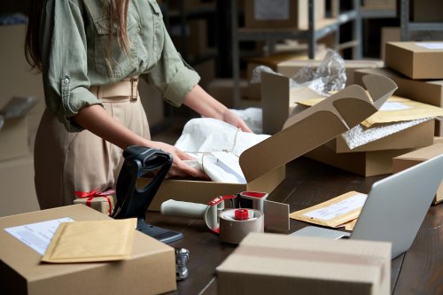 Female small business owner packaging a shipping box